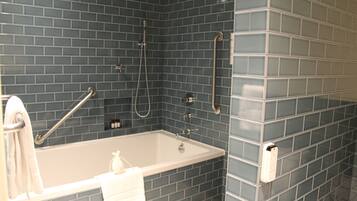 Un baño con bañera, ducha y barras de apoyo.