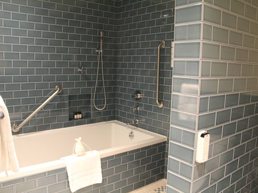 Un baño con bañera, ducha y barras de apoyo.