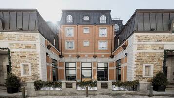 A multi-story building with a stone facade, large windows, and a symmetrical design.