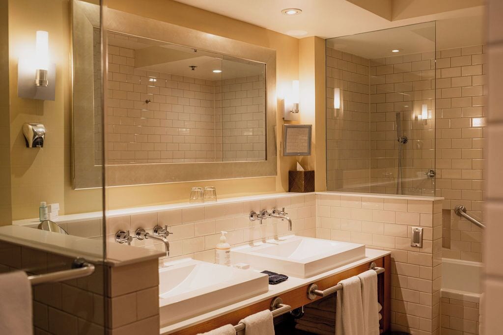 A modern bathroom with two sinks, a large mirror, and a glass-enclosed shower.