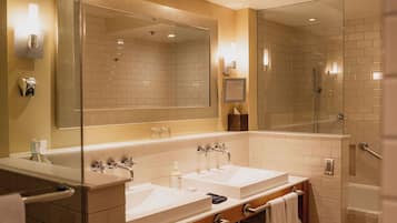 A modern bathroom with two sinks, a large mirror, and a glass-enclosed shower.