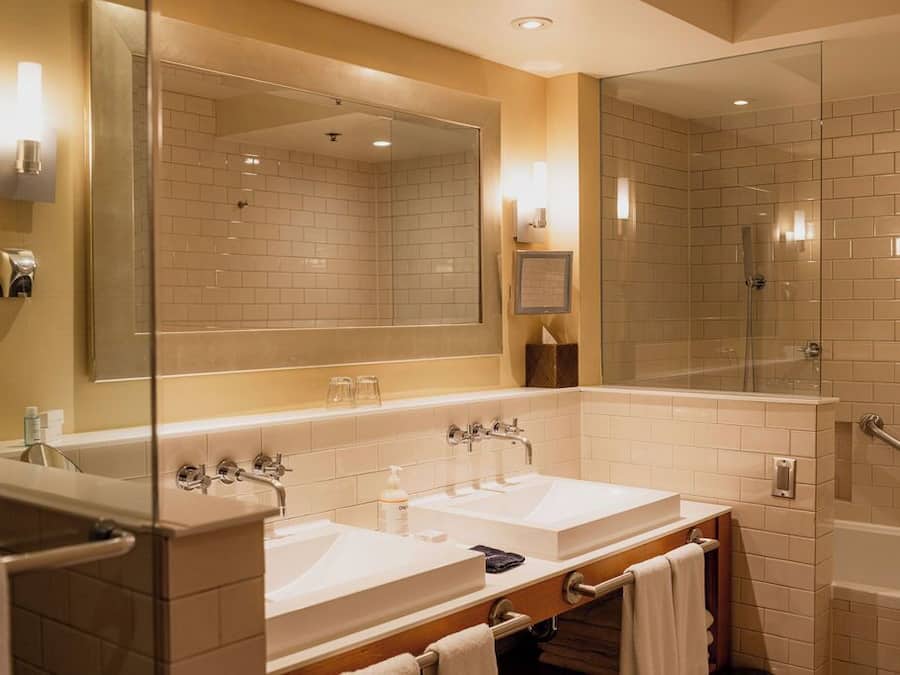 A modern bathroom with two sinks, a large mirror, and a glass-enclosed shower.