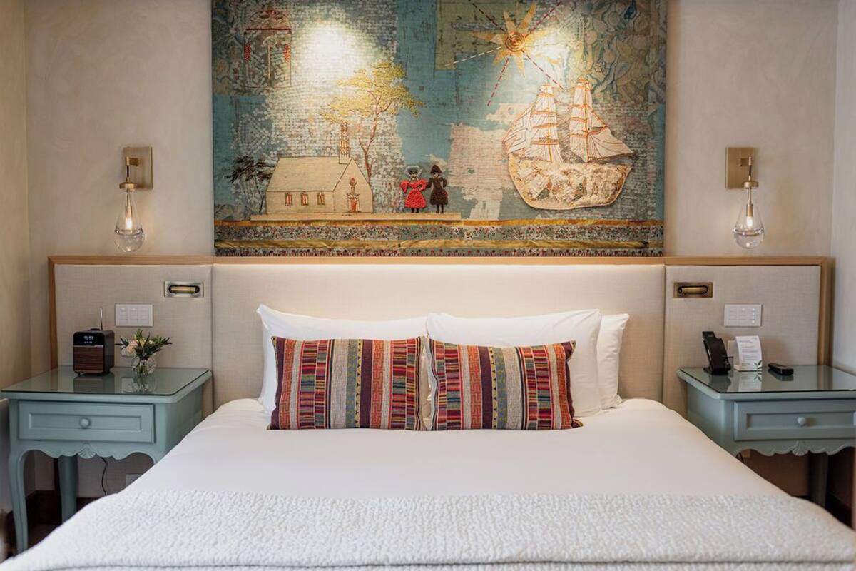 A hotel room with a large bed, two bedside tables, a map artwork on the wall, and a classic design.