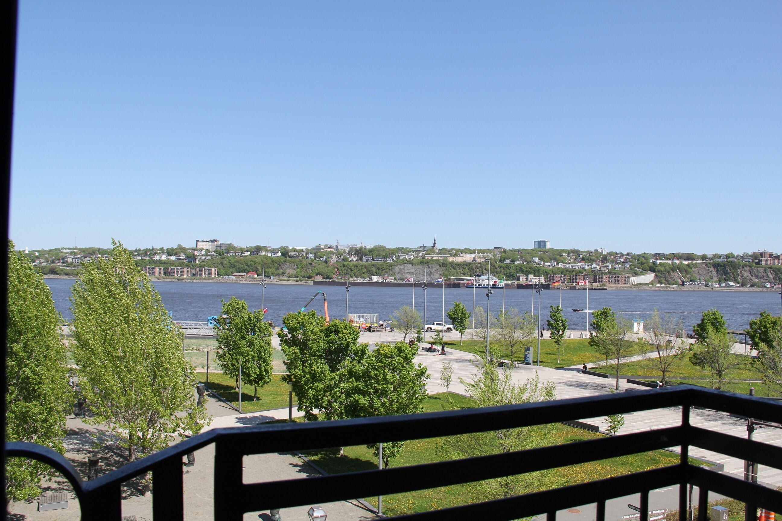 A view of a waterfront area with a clear sky, a river, and a distant cityscape.