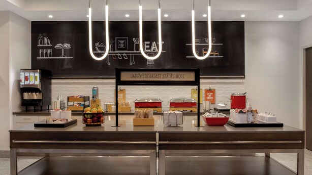 A breakfast buffet setup with a sign that reads "HAPPY BREAKFAST STARTS HERE". - Hampton Inn by Hilton Winnipeg Downtown (Winnipeg)
