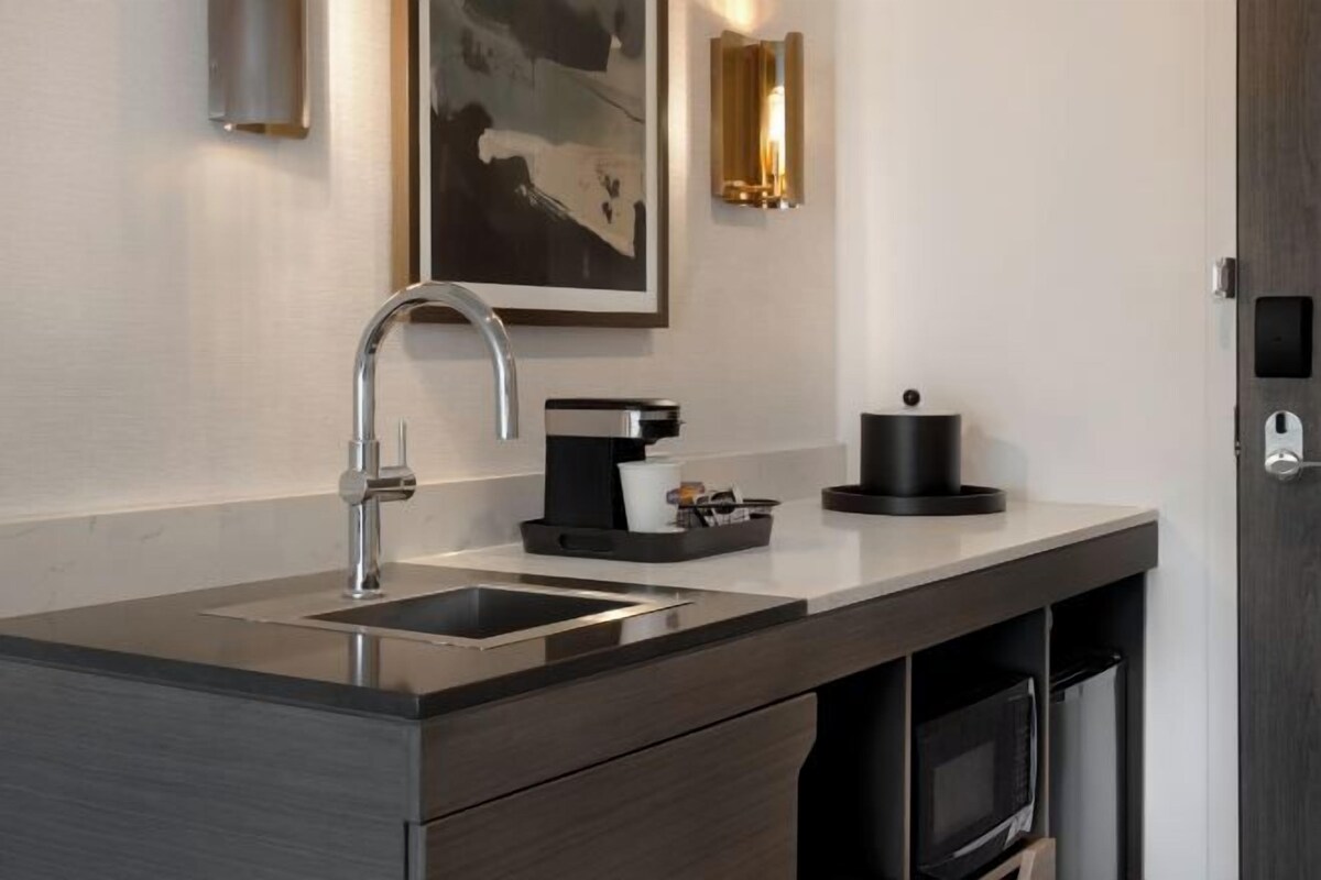 A modern kitchen with a stainless steel sink, a coffee machine, and a microwave.