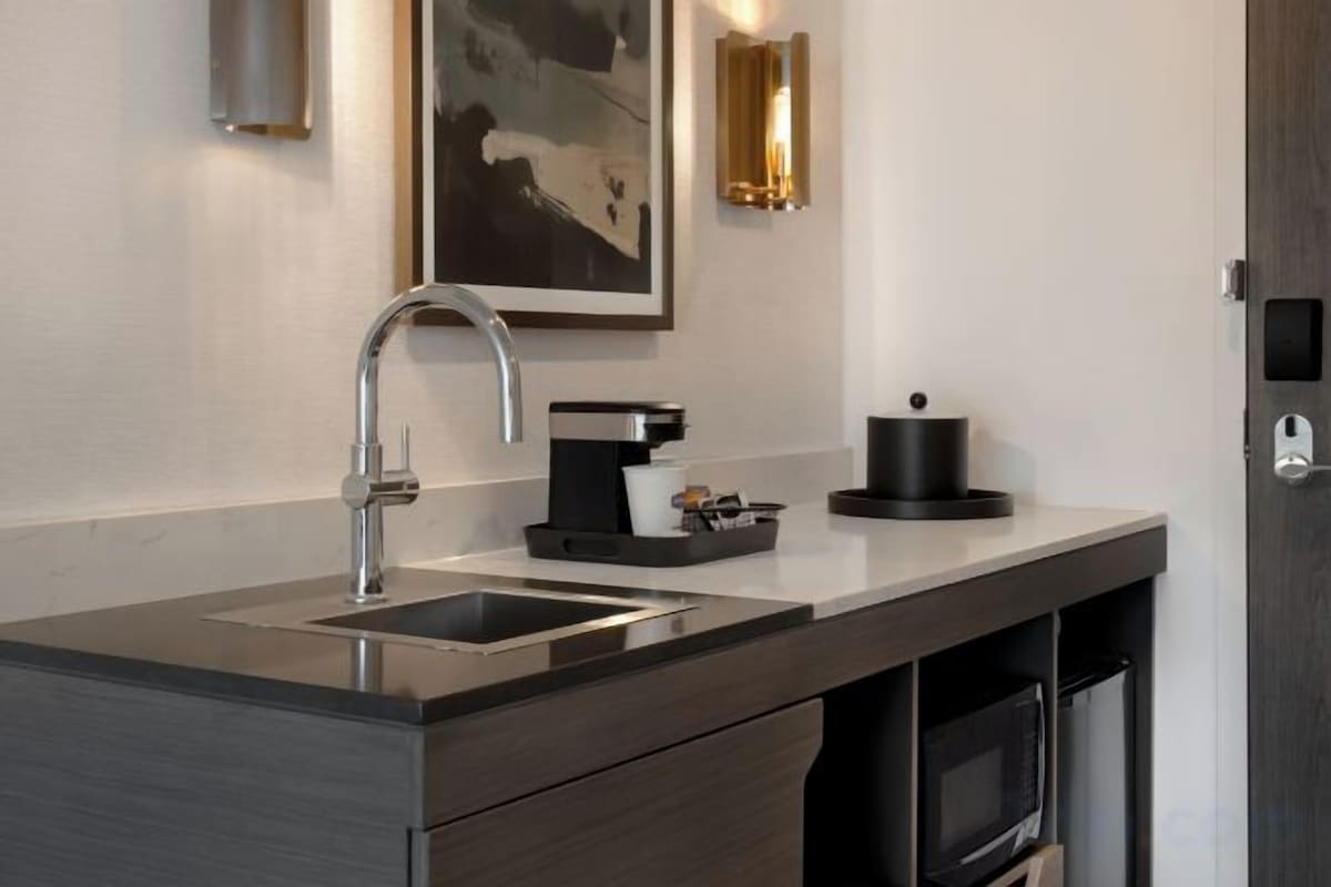 A modern kitchen with a stainless steel sink, a coffee machine, and a microwave.