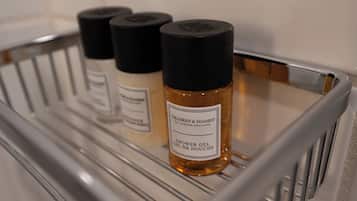 Une étagère de salle de bain avec trois bouteilles de gel douche Gilchrist & Soames.
