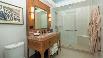 A modern bathroom with a marble vanity, a glass-enclosed shower, and a robe hanging on the wall.