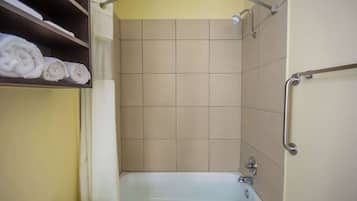 Un bagno con una vasca, uno scaffale con asciugamani e una zona doccia.