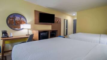 A hotel room with two beds, a desk with a flat-screen TV, a coffee maker, and a microwave.
