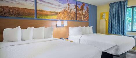 A hotel room with two beds, a large landscape mural, a wooden headboard, a nightstand, and a window with curtains.