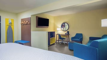 Habitación de hotel con cama, escritorio, silla, sofá, televisión y espejo.