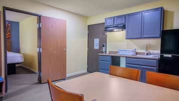 A compact kitchen with a dining area, wooden cabinets, and a TV.