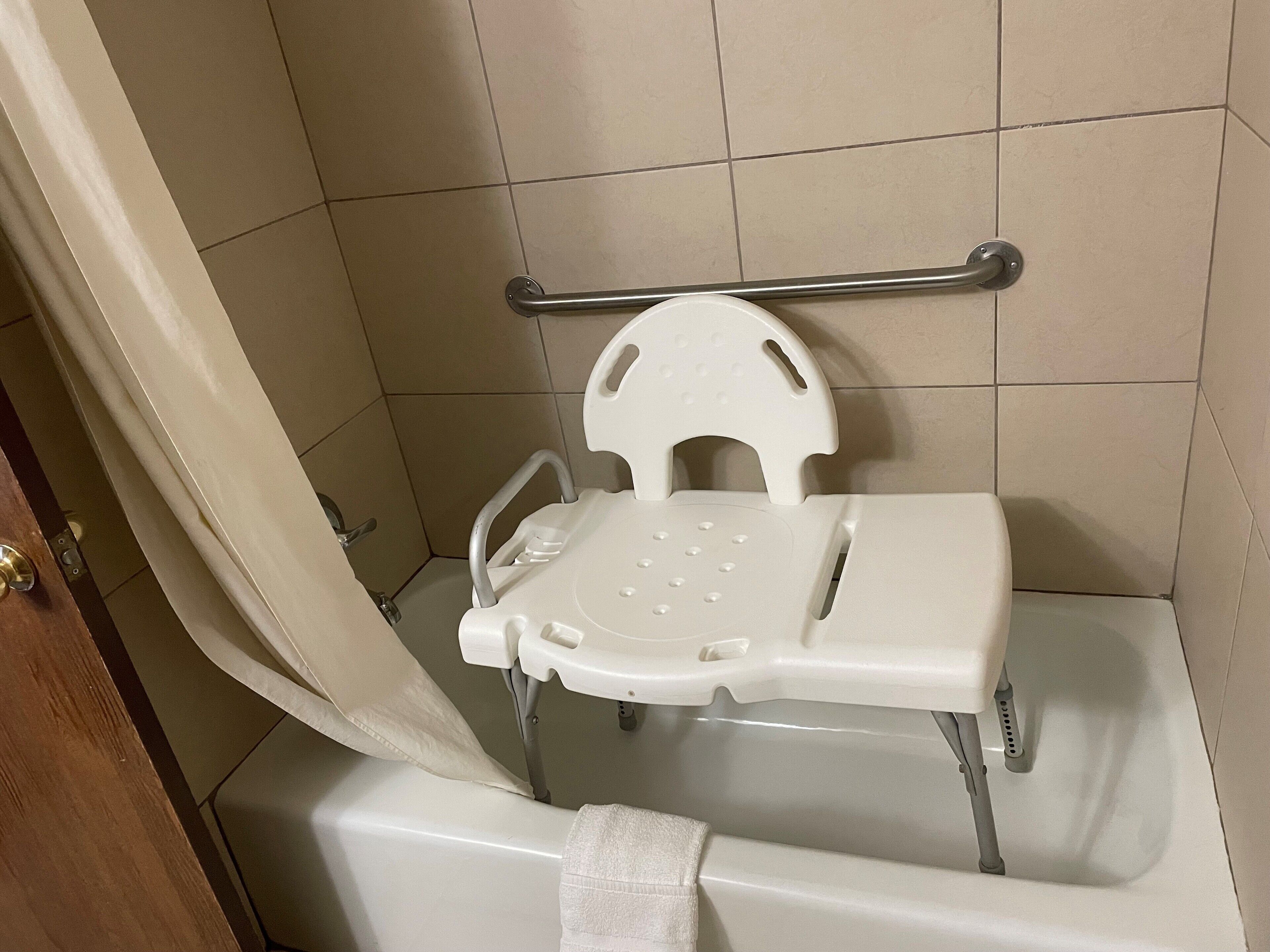 Un baño con inodoro blanco, barra de apoyo y cortina de ducha.