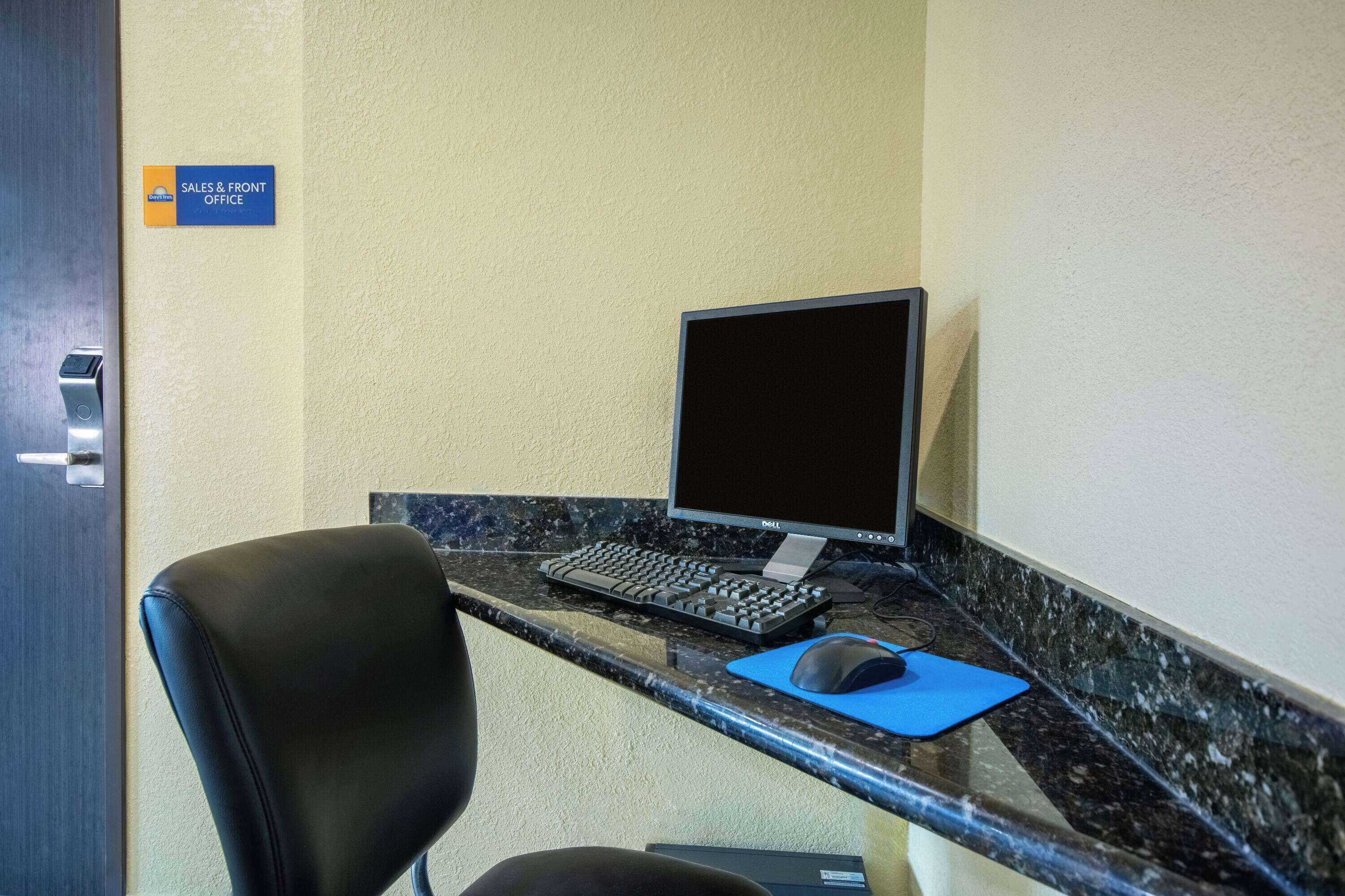 A reception desk with a computer, keyboard, mouse, and a sign indicating the sales and front office.