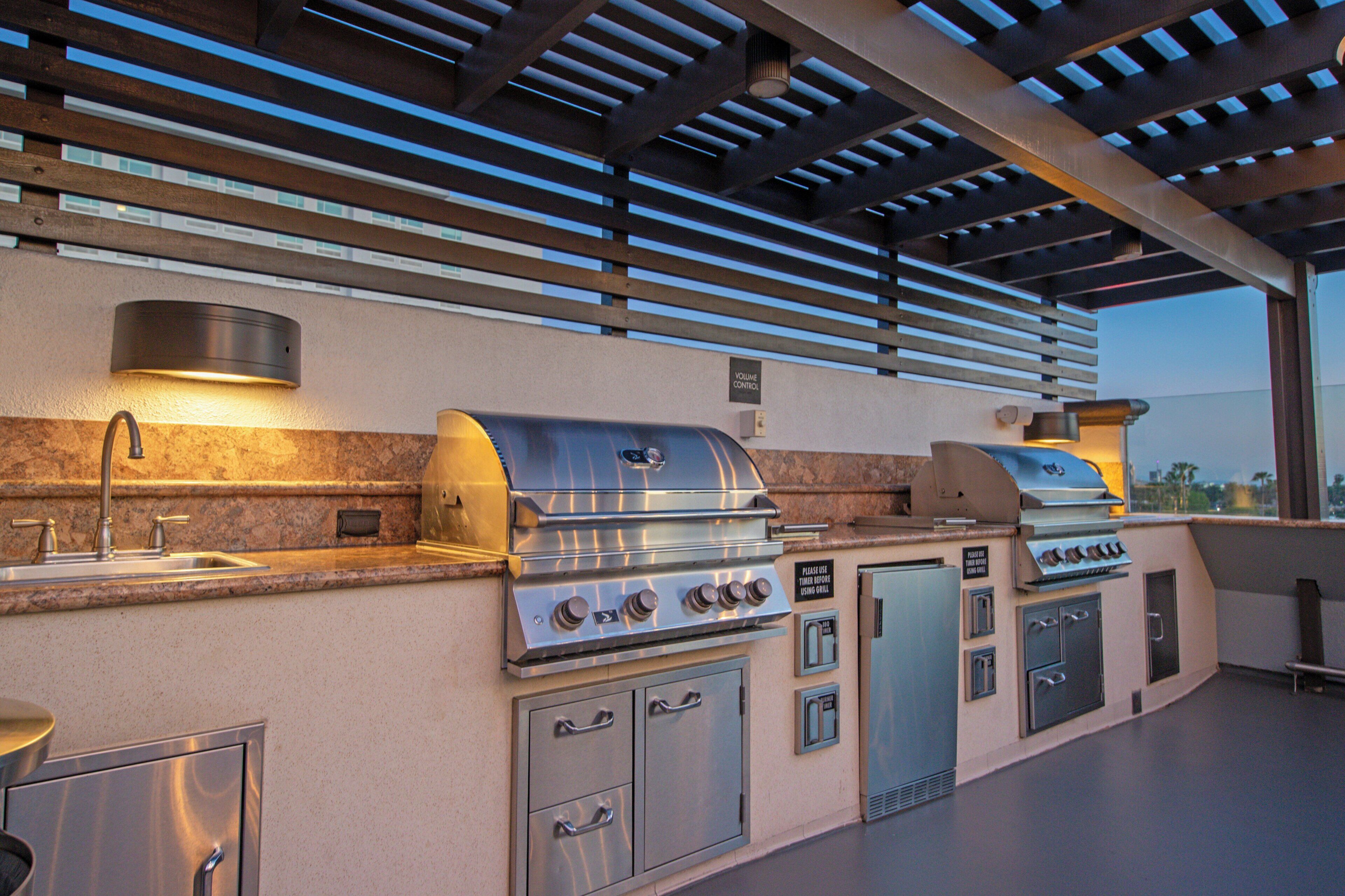 Cocina exterior con una parrilla empotrada, un fregadero y armarios de almacenamiento.