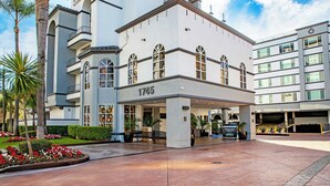 A modern hotel with a prominent address number, a covered entrance, and a landscaped courtyard. - Peacock Suites (Anaheim)