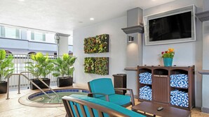 A pool area with a chair, a table, a towel return station, and potted plants. - Peacock Suites (Anaheim)