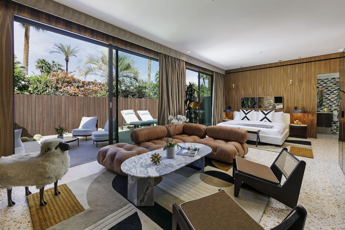 A modern living room with a large window, a sofa set, a coffee table, and a small table with a lamp.