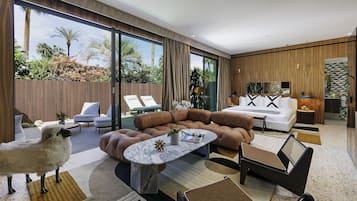 A modern living room with a large window, a sofa set, a coffee table, and a small table with a lamp.