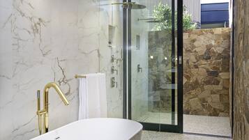 Ein modernes Badezimmer mit einer freistehenden Badewanne, einer gläsernen Duschkabine und einer Wand aus Stein.