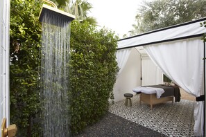 A spa room with a shower, a bed, and a small table.
