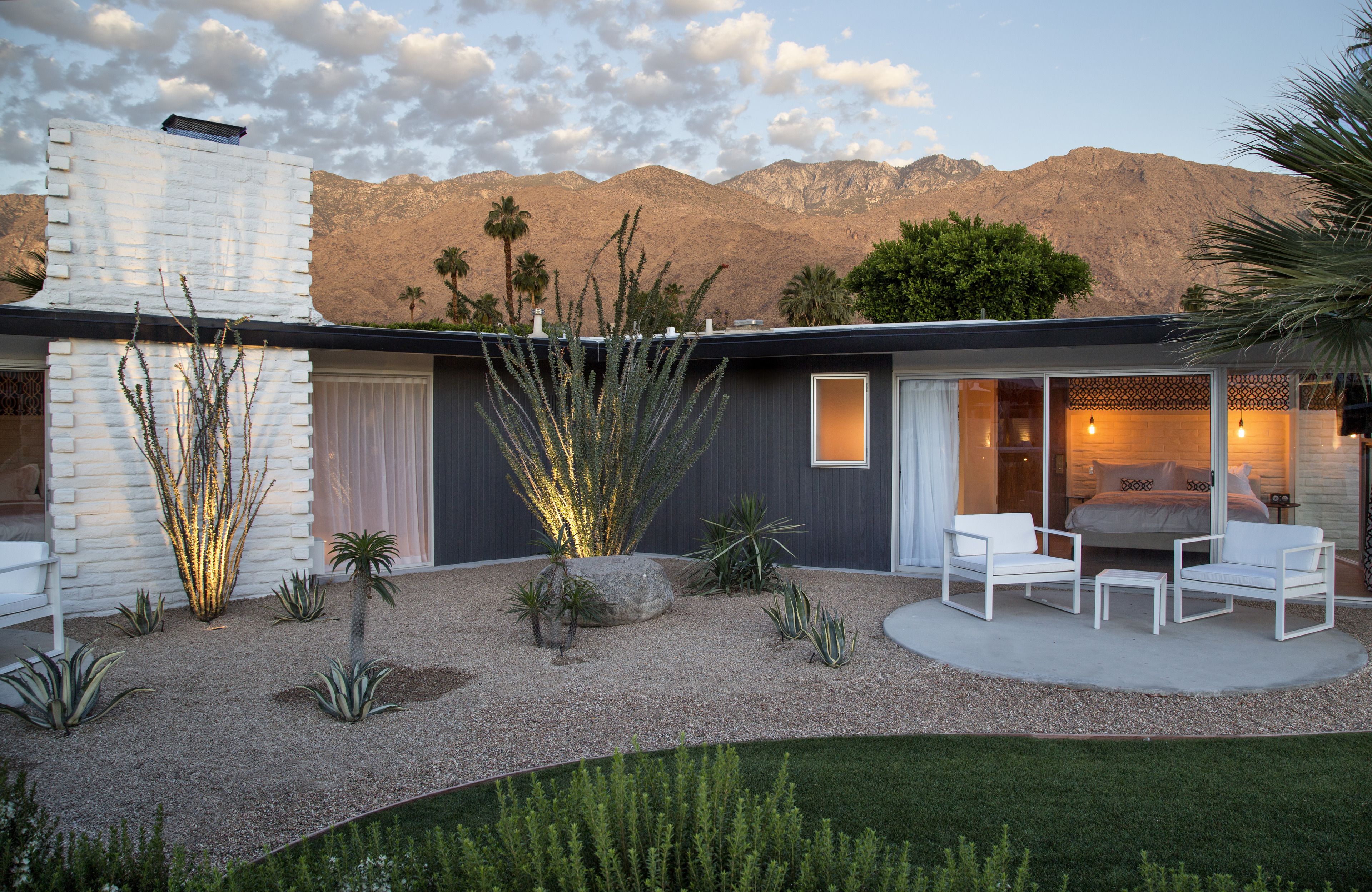 A modern house with a patio area featuring a seating arrangement and a large plant.