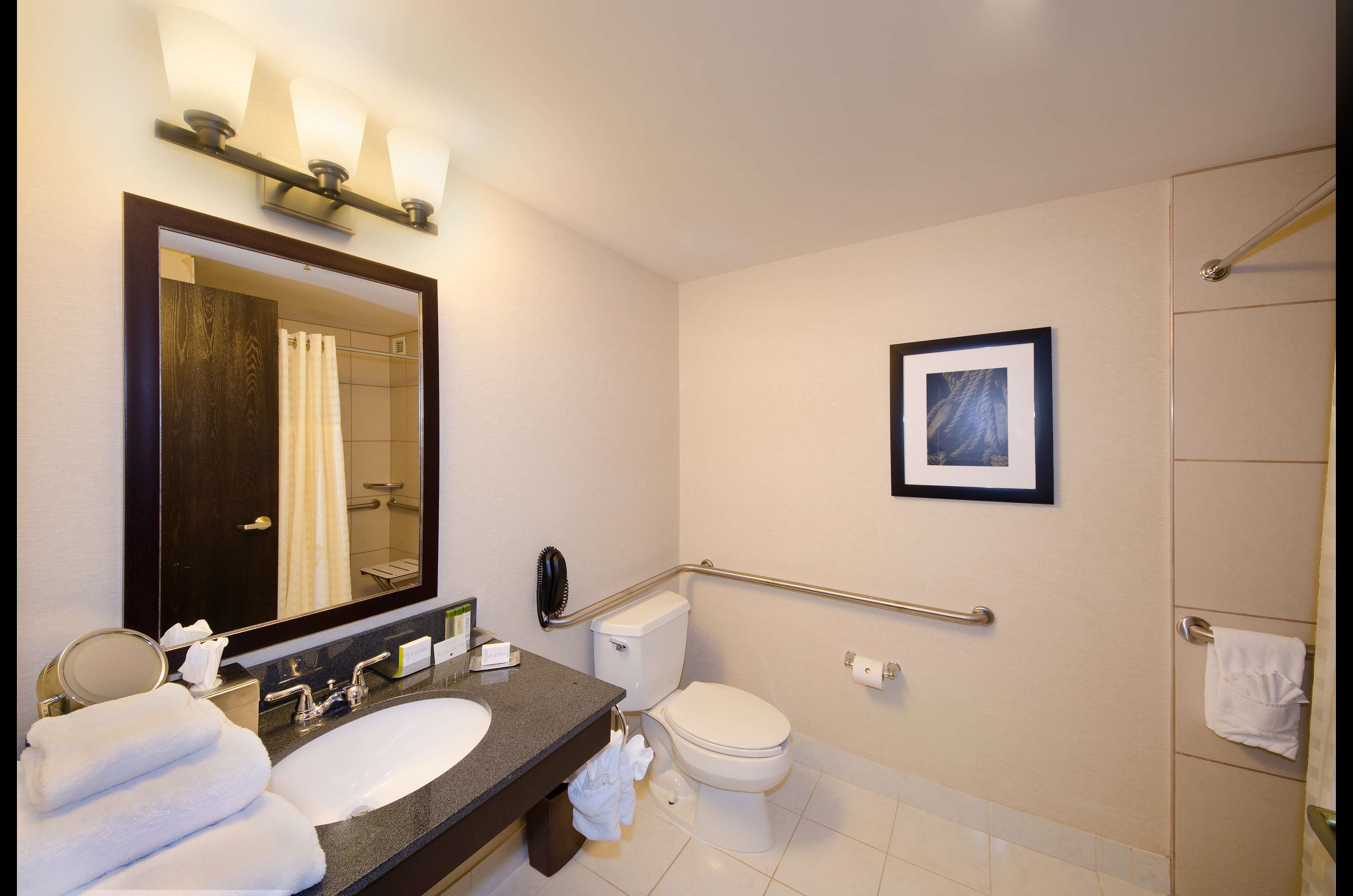 A modern bathroom with a large mirror, a sink, a toilet, and a shower area.