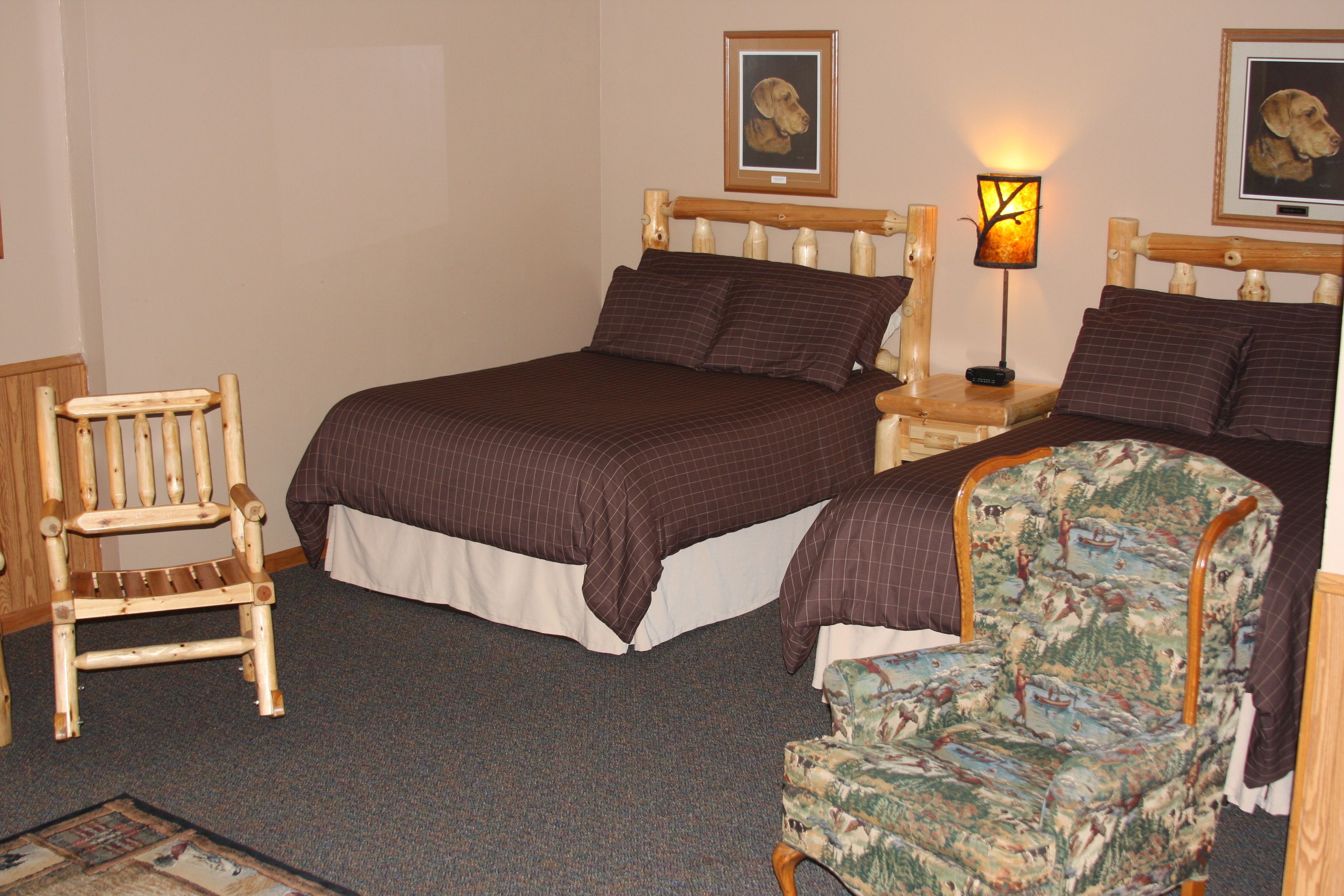 A bedroom with a large bed, two nightstands, a wooden chair, and a patterned armchair.