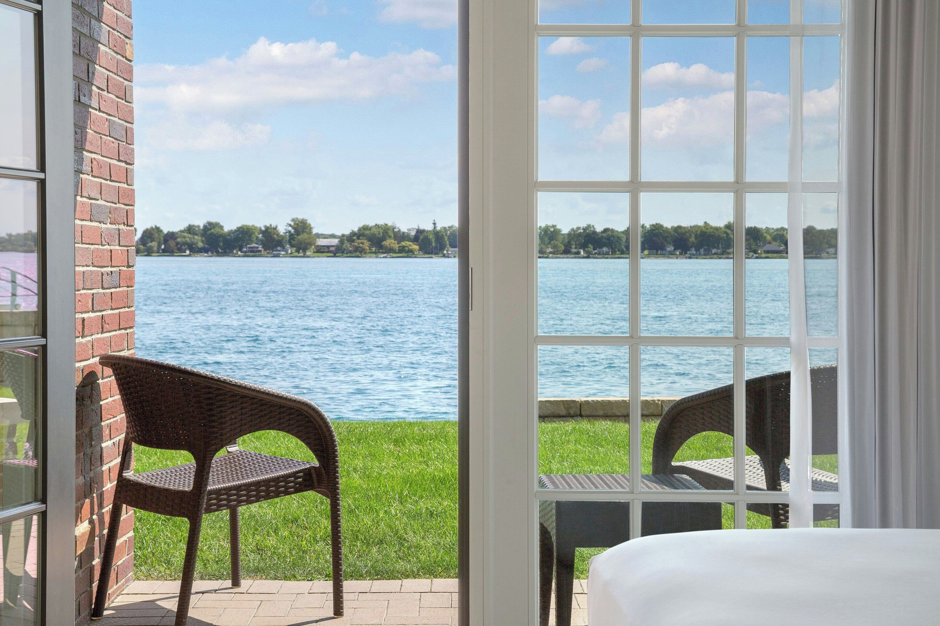 Une chambre avec vue sur un lac, des fauteuils en osier et un lit.