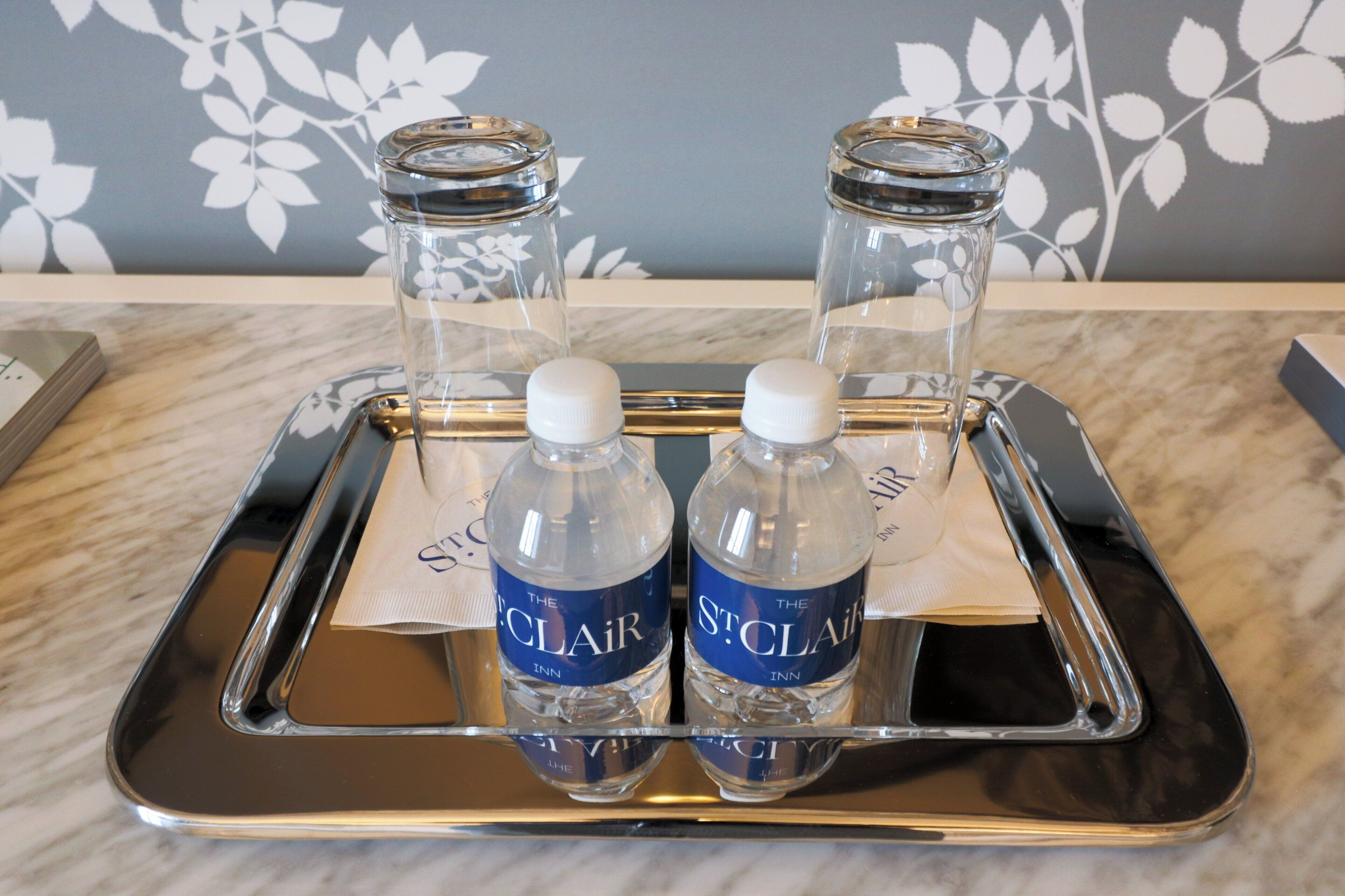 A tray with two water bottles and two glass containers on a marble surface.
