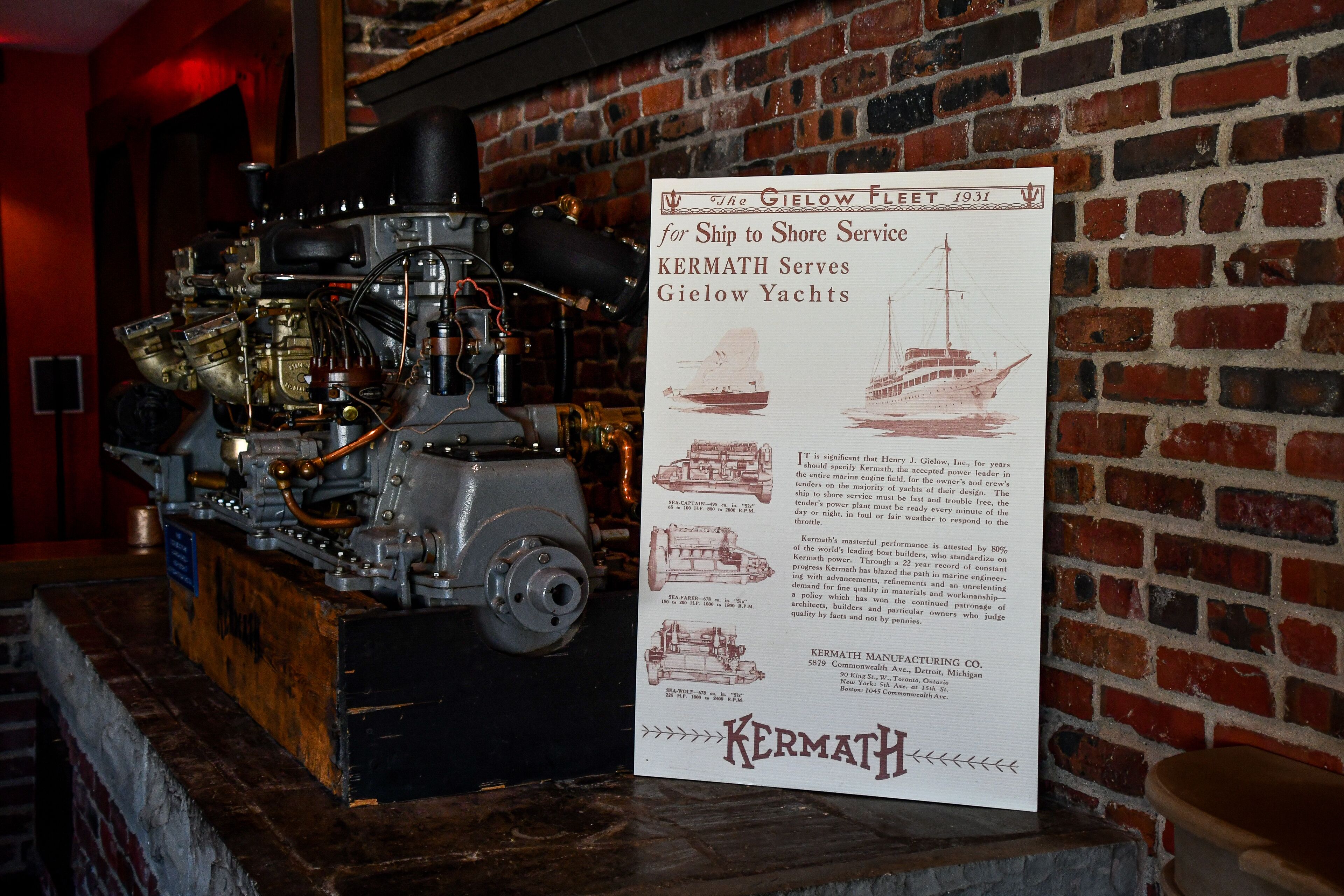 A vintage marine engine with a detailed informational sign about Kermath Manufacturing Co.
