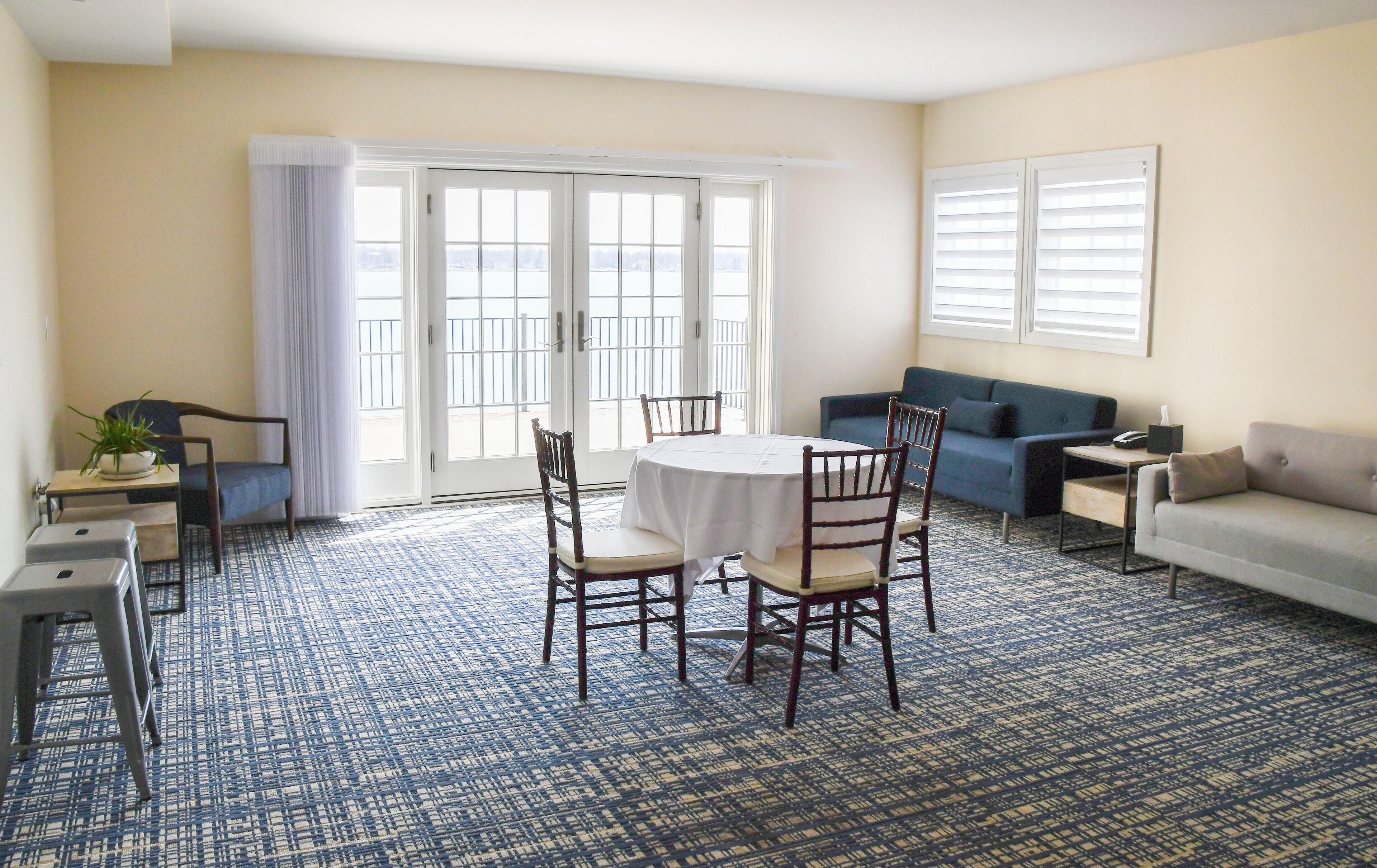 A living room with a dining table, chairs, a sofa, and a blue patterned carpet.