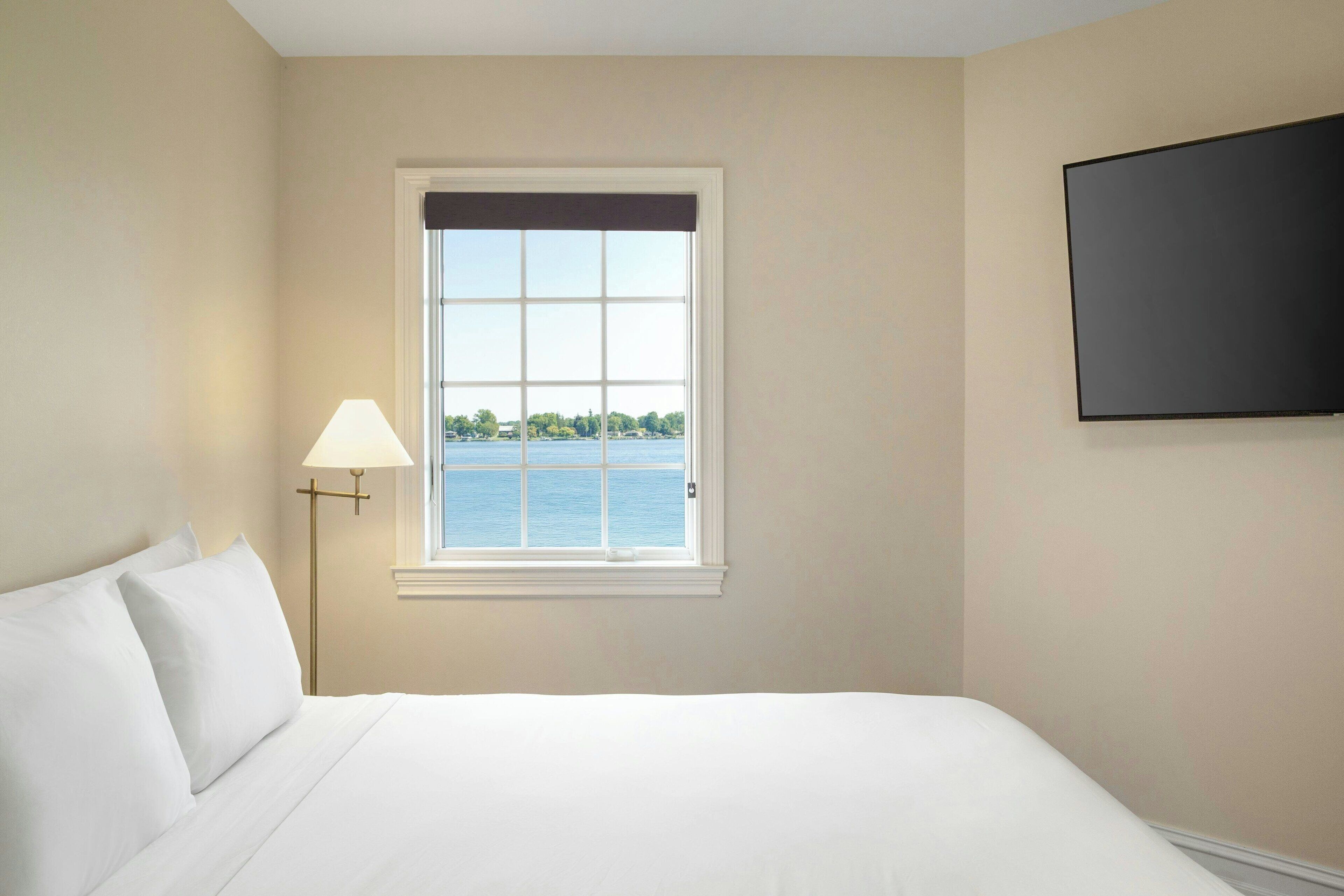 Camera d'albergo con un letto grande, una finestra vista mare e una TV a schermo piatto montata a parete.