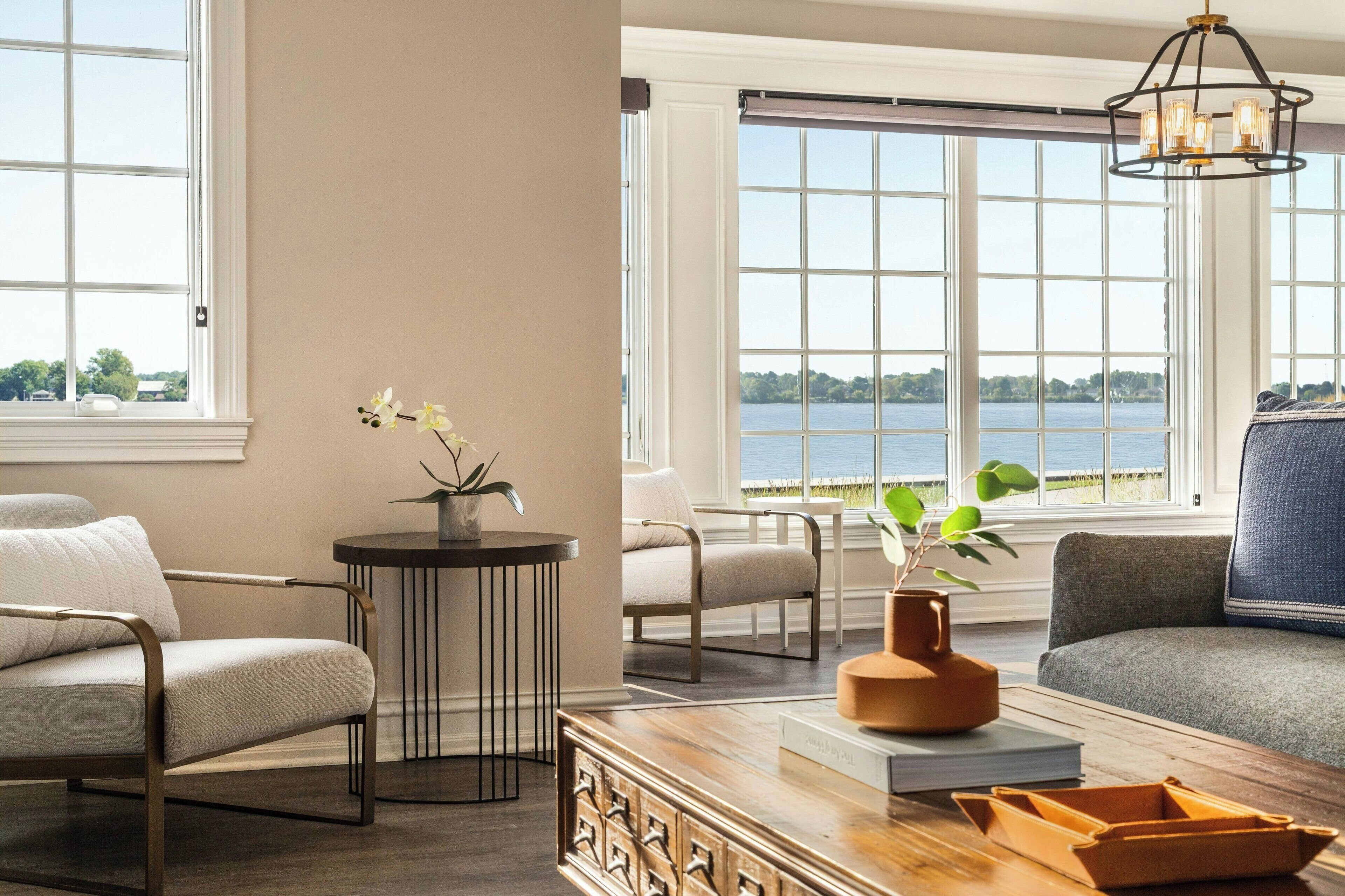Una sala de estar moderna con vistas a un lago, una mesa de centro de madera, un sofá y una silla.