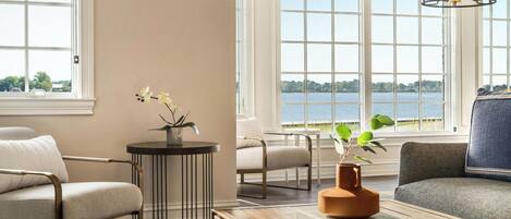 Una sala de estar moderna con vistas a un lago, una mesa de centro de madera, un sofá y una silla.