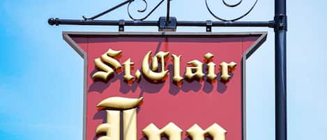 A sign for St. Clair Inn with a red background and gold lettering.