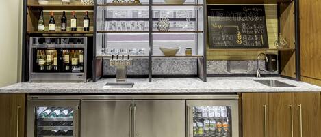 Una cocina con botellas de vino, vasos y un menú en una pizarra.
