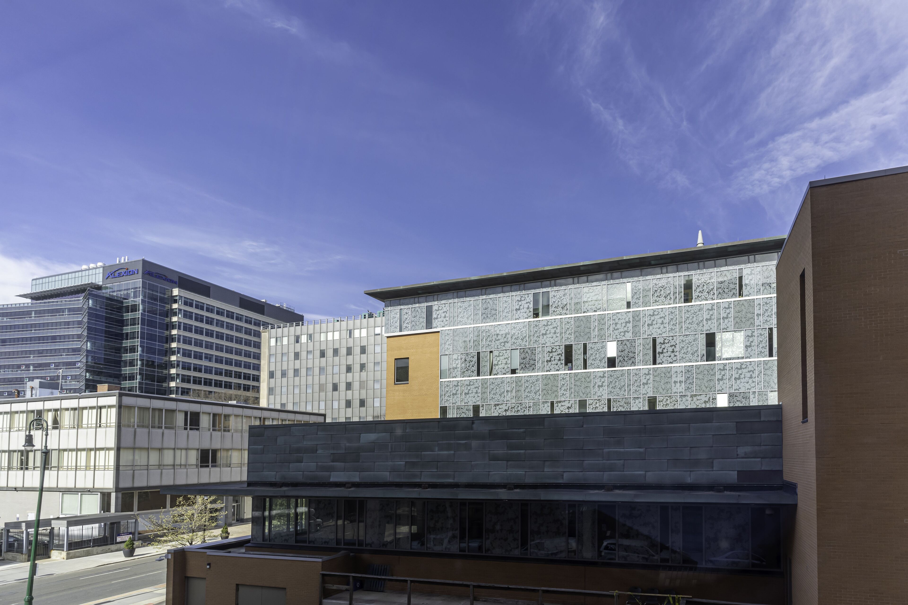 Een modern gebouw met een glazen gevel, een gele accentmuur en een bakstenen gedeelte.