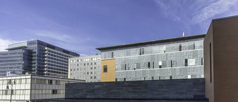 Een modern gebouw met een glazen gevel, een gele accentmuur en een bakstenen gedeelte.