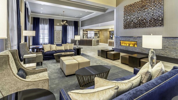 A spacious lobby with a sofa, armchairs, and a coffee table. There is a fireplace and a wall-mounted artwork. - New Haven Hotel (New Haven)