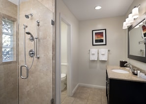 Une salle de bain équipée d’une douche, de toilettes, d’un lavabo et d’un tableau encadré au mur.