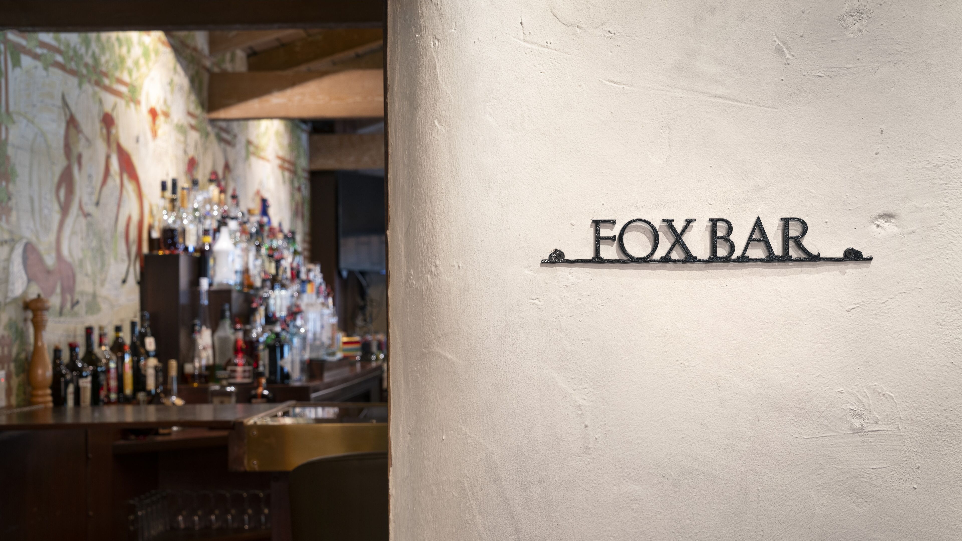 Eine Barbereich mit einem Schild mit der Aufschrift "FOXBAR" und einer Wand mit einem Wandgemälde.