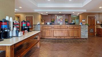 A reception area with a wooden counter, coffee machines, and a stone accent wall.