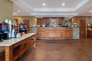A reception area with a wooden counter, coffee machines, and a stone accent wall.