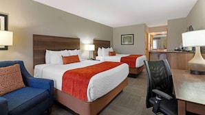 A hotel room with two beds, a desk, a chair, and a couch.