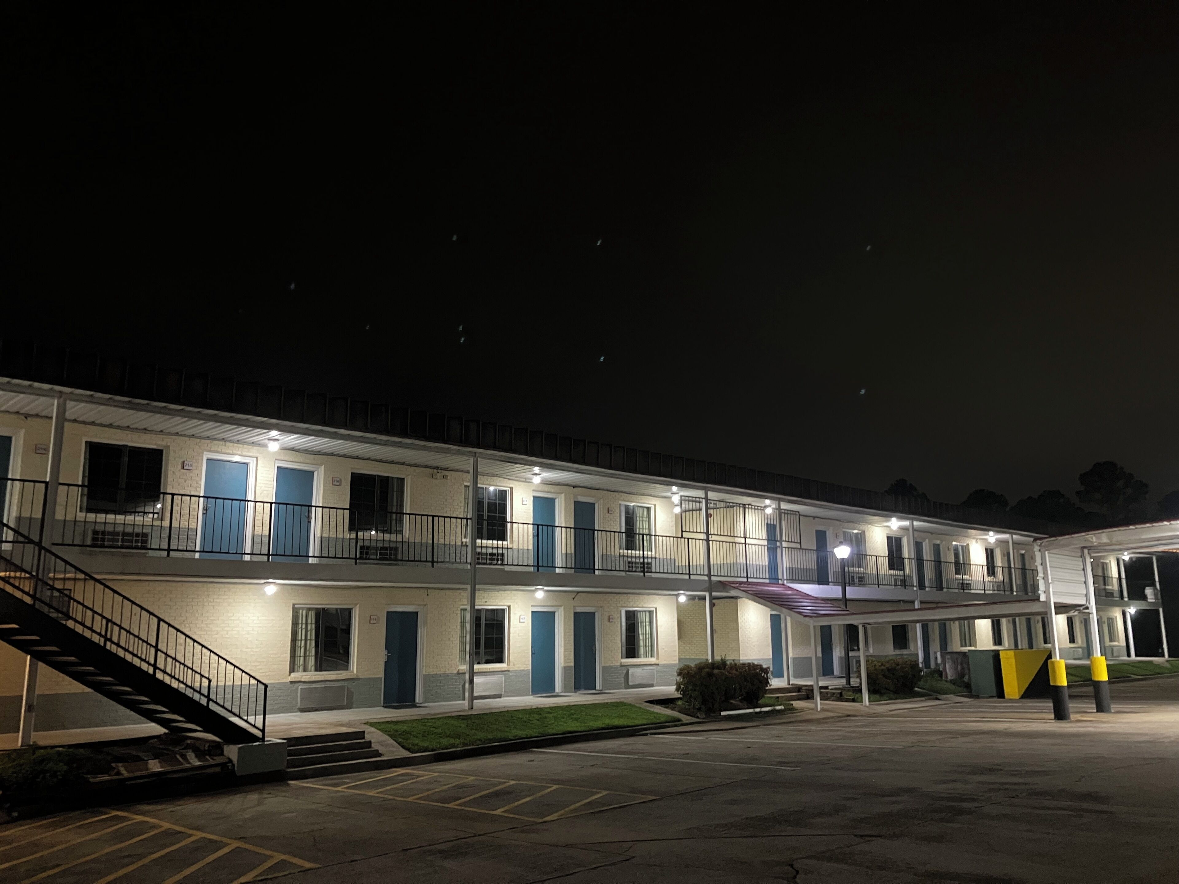 Et motel med flere etager, parkeringsdæk og en trappe, der fører til indgangen.