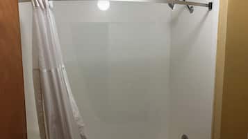 A shower with a white curtain, a handheld showerhead, and a wall-mounted faucet.