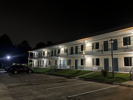 Un motel de varios pisos con estacionamiento, una escalera y una farola.